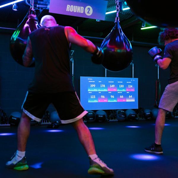 Man performing a controlled strength exercise in a modern, dark gym.